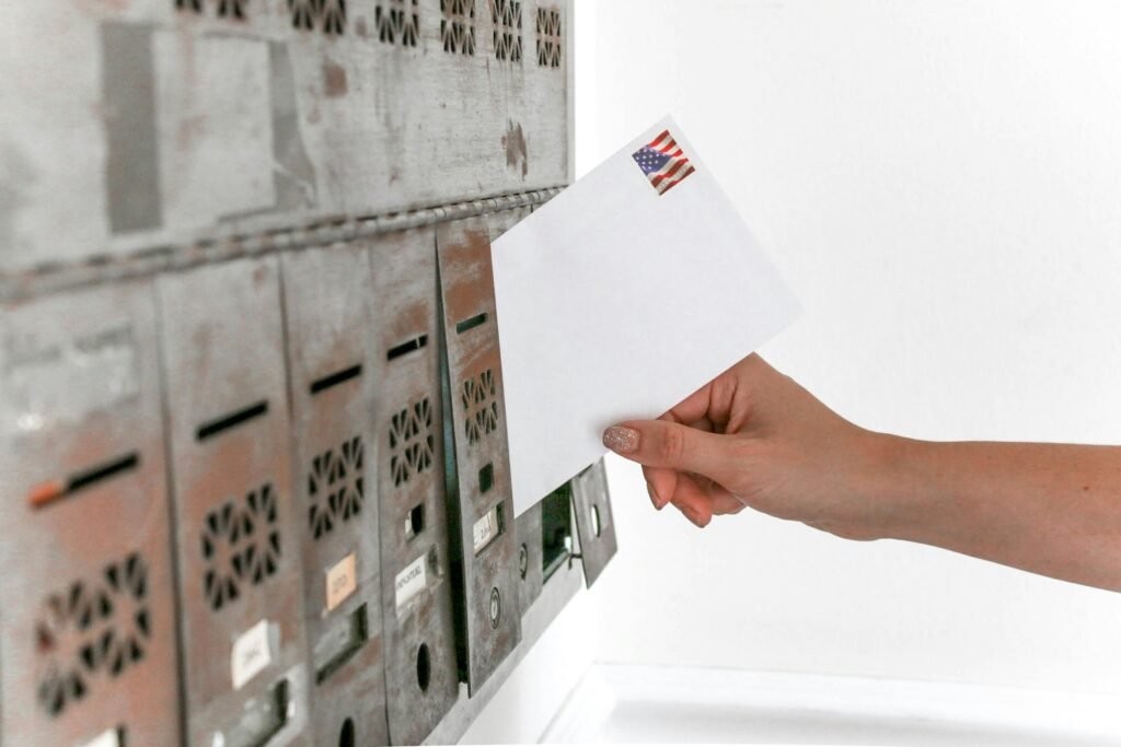 pexels-photo-1550334-1550334 Close-up of a hand inserting a stamped envelope into a mailbox, symbolizing voting.